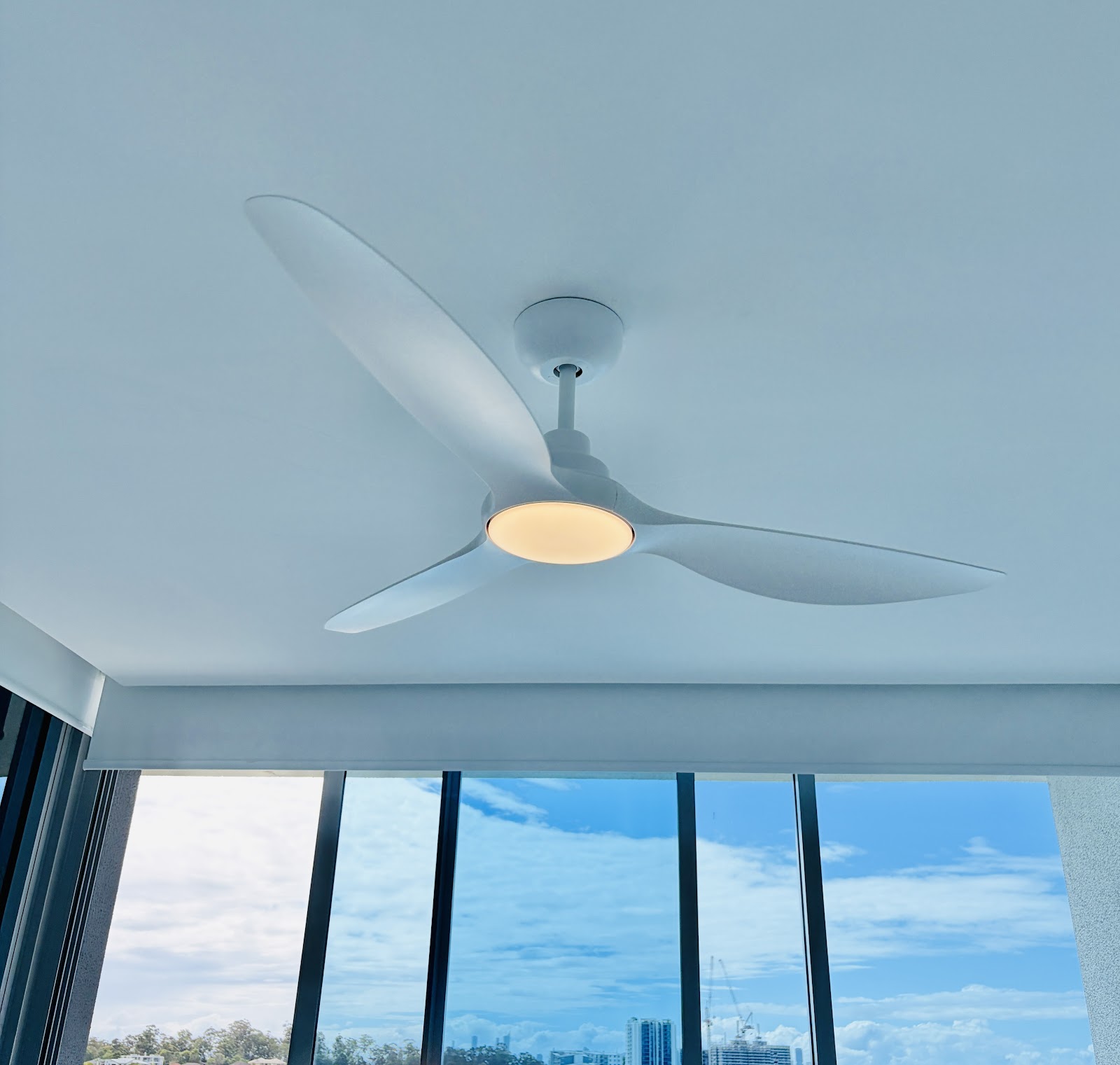 White ceiling fan with LED light in a bright room with tall windows