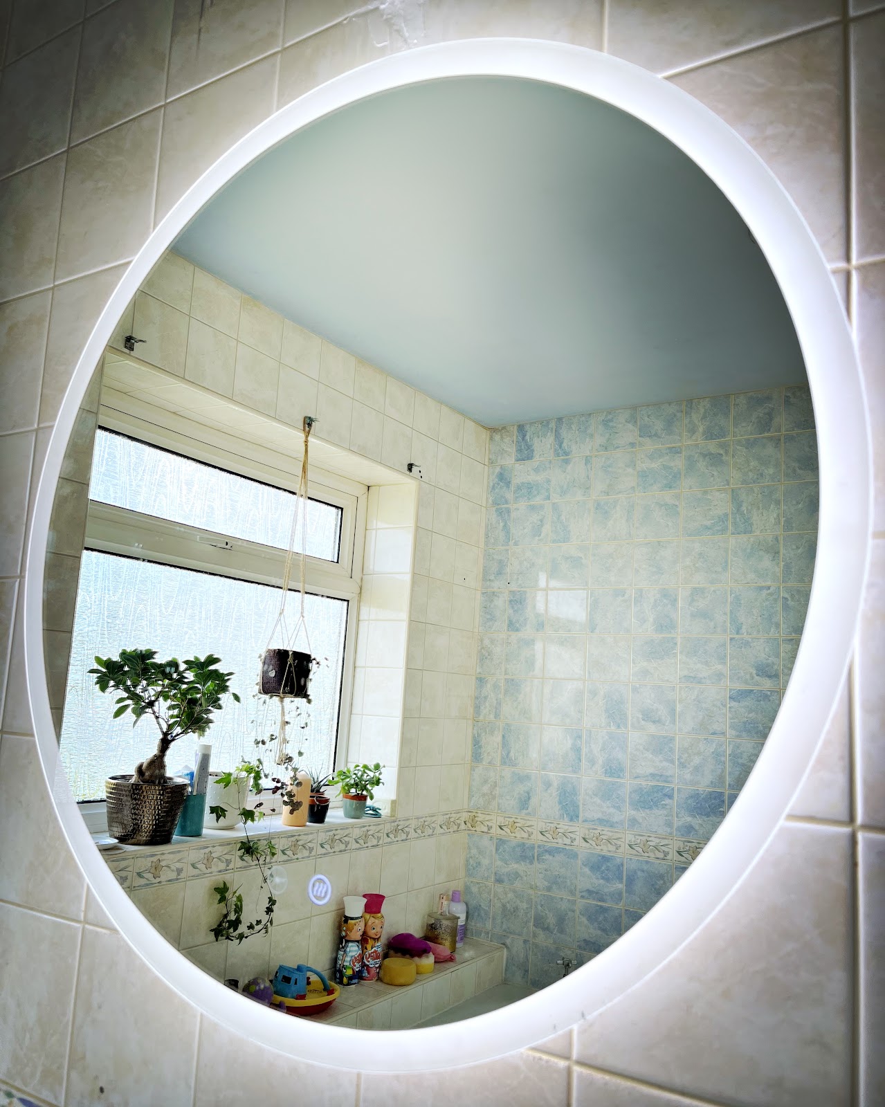 Large round backlit LED mirror in a tiled bathroom
